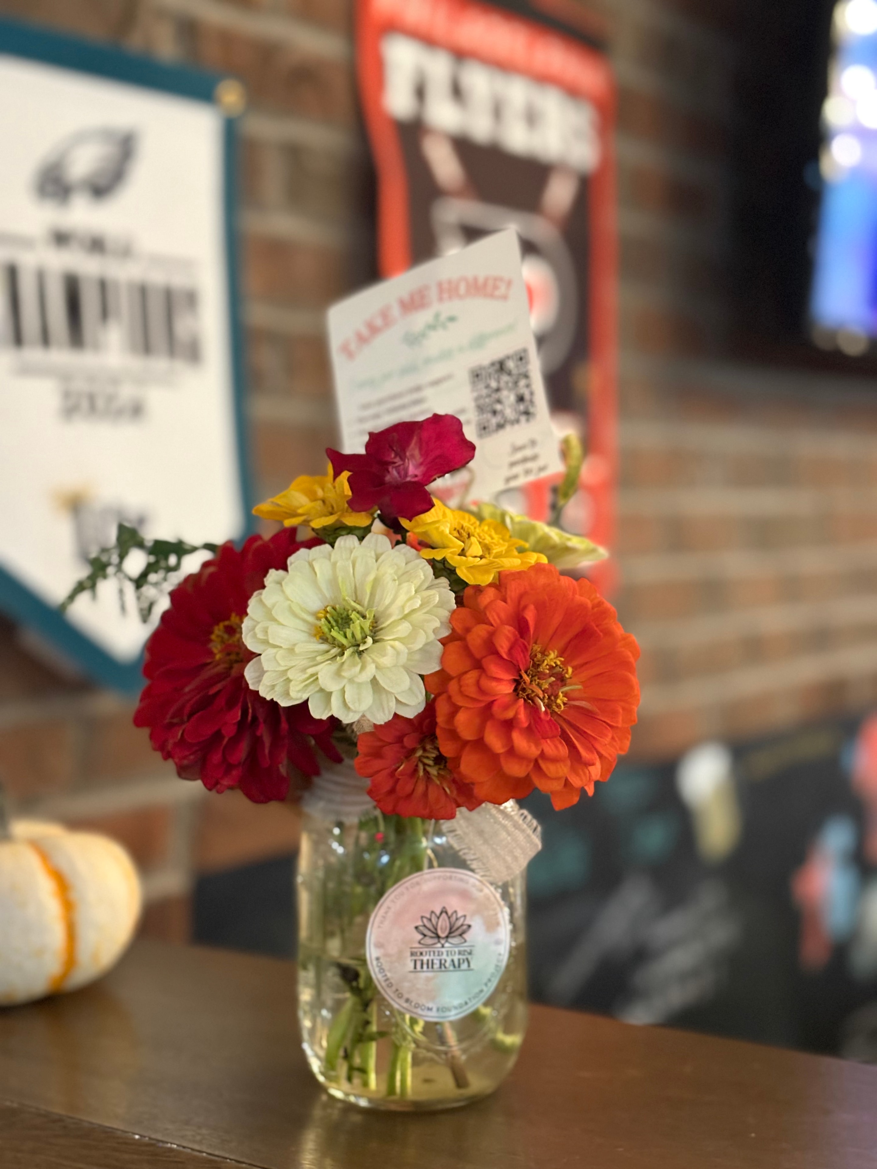 Colorful zinnia bouquet in mason jar with Rooted to Rise Therapy sticker and Take Me Home card