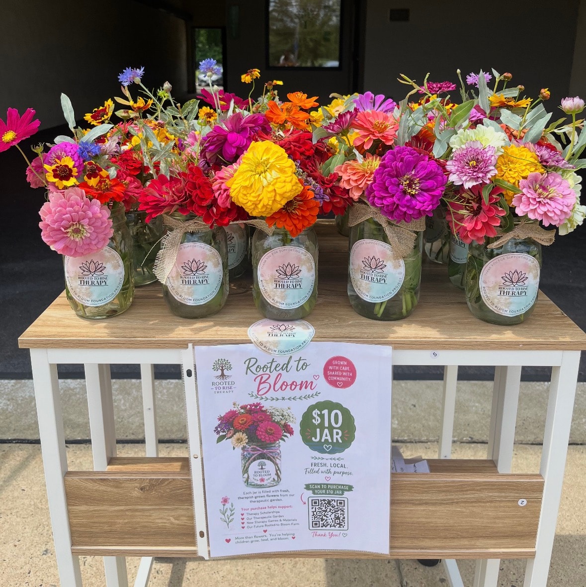 Rooted to Bloom flower stand display with branded jars and $10 jar signage